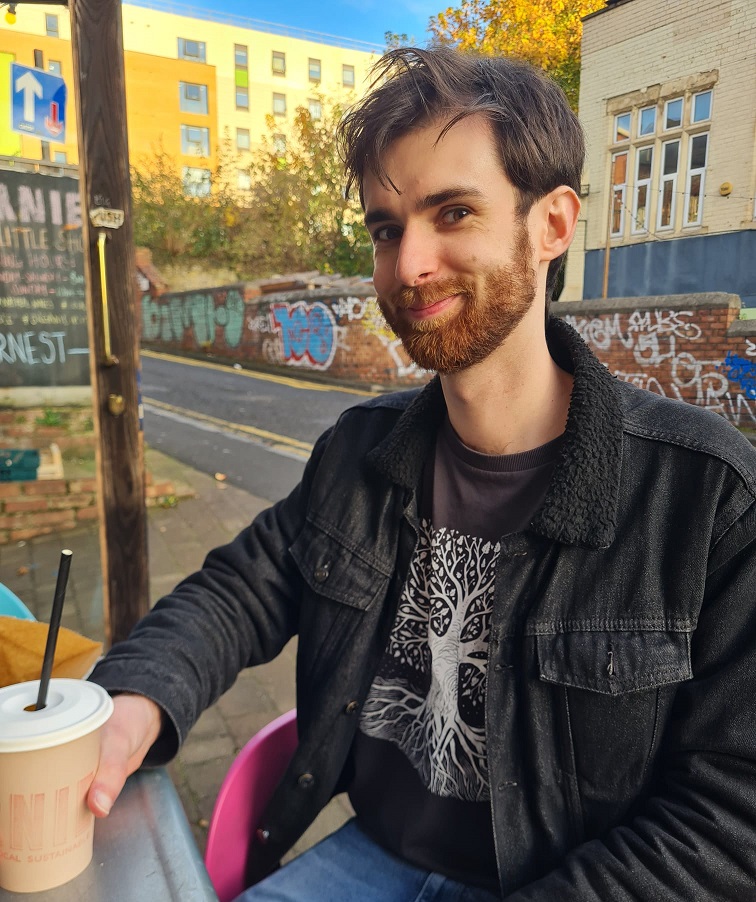 A photo of the editor, Nathaniel Spain, sitting outside and smiling.
